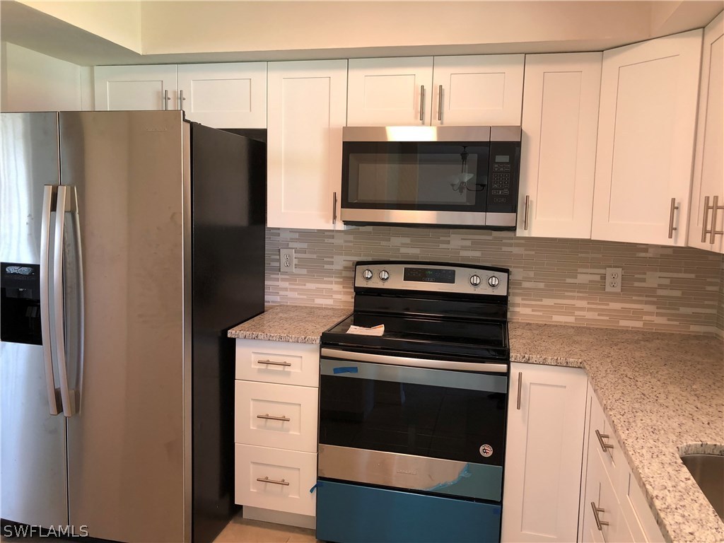 19 Connecticut Road Lehigh Acres, FL 33936 - Photo 4 of 26 a kitchen with a stove and a microwave