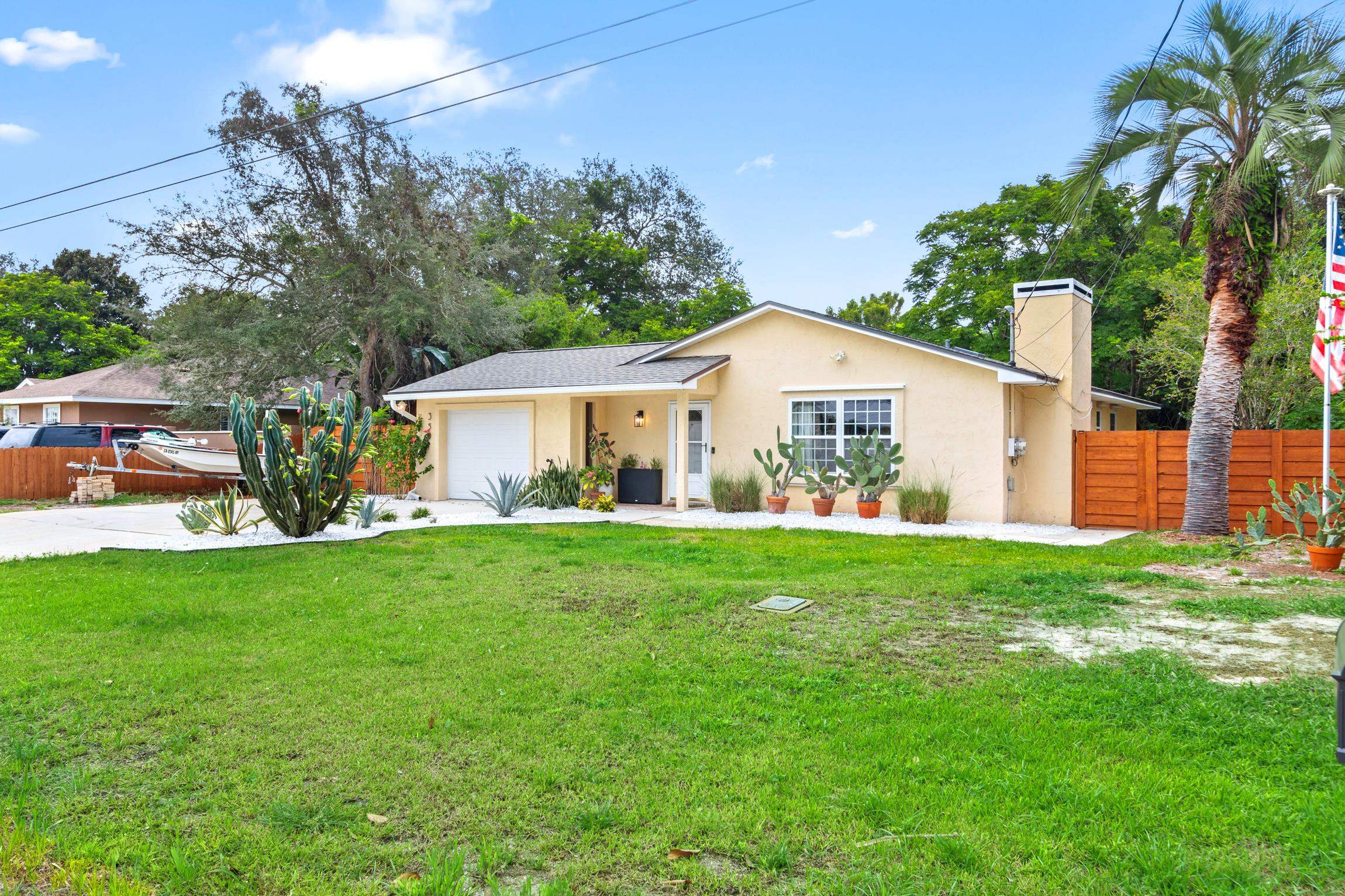 359 Shamrock Road St. Augustine, FL 32086 - Photo 3 of 39 a view of a house and garden with a table and chairs under an umbrella
