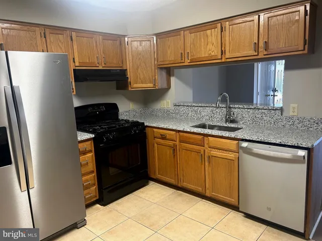 a kitchen with granite countertop a refrigerator and a sink