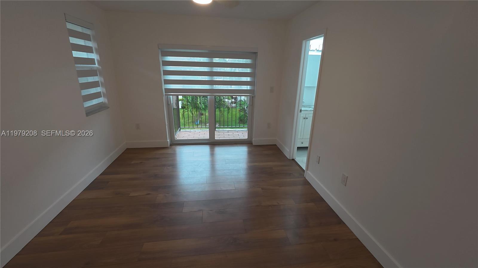 7121 Southwest 129th Avenue, Unit 8 Miami, FL 33183 - Photo 11 of 13 a view of an empty room with wooden floor and a window