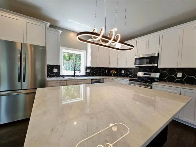 a kitchen with stainless steel appliances granite countertop a refrigerator a stove a microwave oven a sink a dining table and chairs with wooden floor