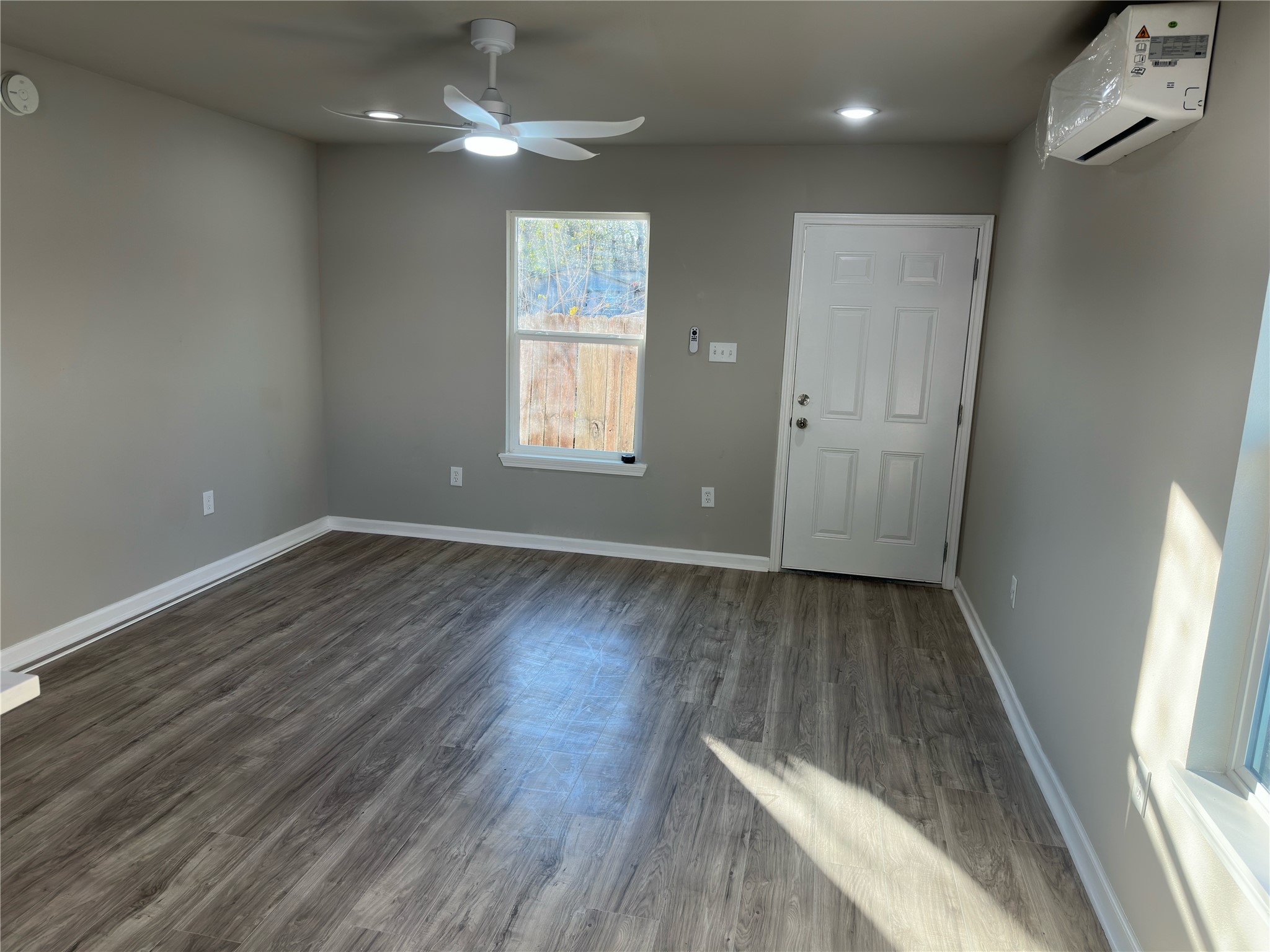 9935 Algiers Road, Unit B Houston, TX 77041 - Photo 3 of 6 an empty room with wooden floor and windows
