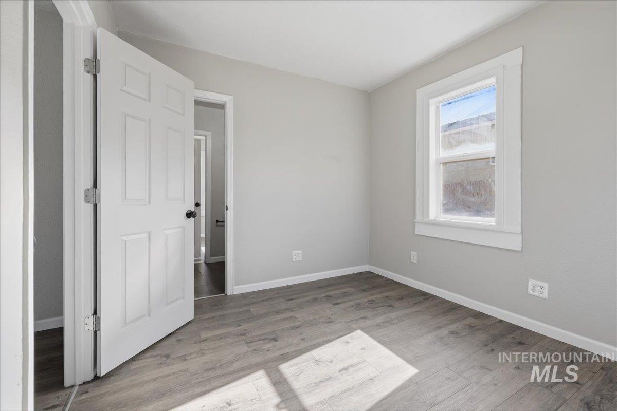 284 Fargo Avenue Notus, ID 83656 - Photo 14 of 24 Room featuring light gray painted walls, wood-finish flooring, a white trim window, and a white paneled door with a black doorknob