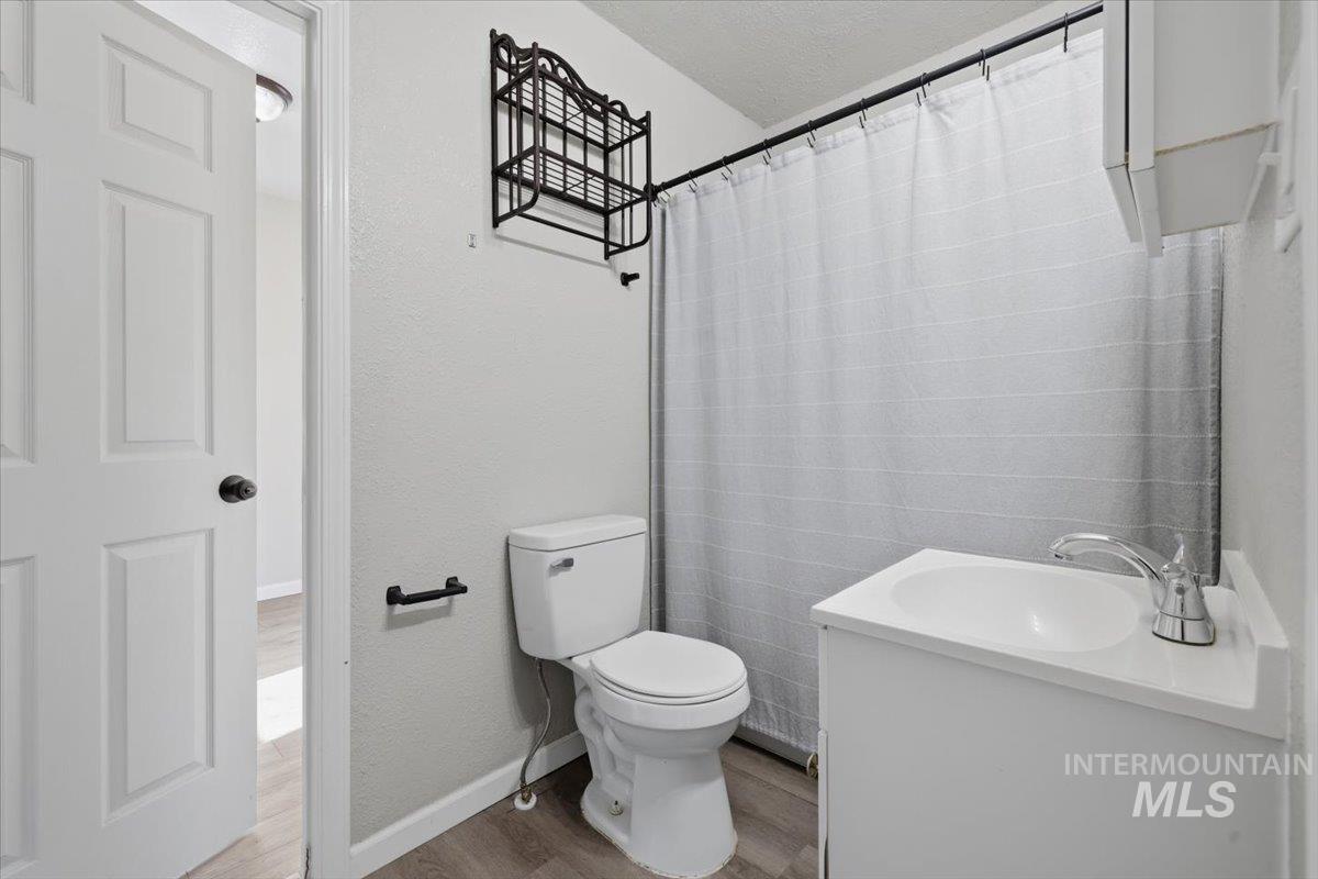 284 Fargo Avenue Notus, ID 83656 - Photo 20 of 24 Full bathroom featuring a white vanity with integrated sink, chrome faucet, toilet, and wood-finish flooring