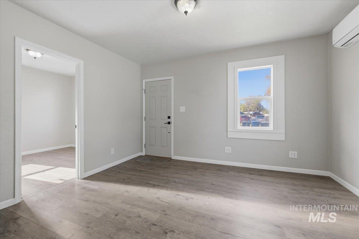 284 Fargo Avenue Notus, ID 83656 - Photo 3 of 24 Interior space with light gray walls, wood-finish flooring, a white trim window, a white five-panel door, and an overhead lighting fixture