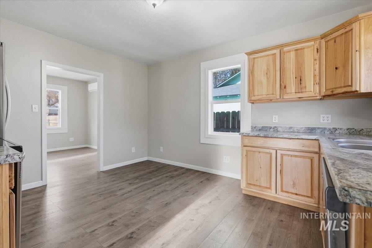 284 Fargo Avenue Notus, ID 83656 - Photo 10 of 24 Kitchen area featuring wood-finish flooring, light-toned cabinetry, light-colored countertops, a double basin sink, and a built-in dishwasher