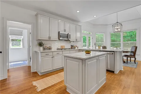 a kitchen with kitchen island granite countertop a sink and a stove top oven with wooden floor