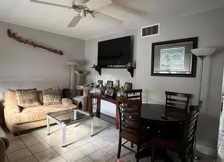 a living room with furniture a flat screen tv and kitchen view