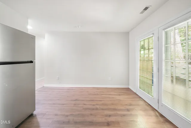 a view of an empty room with wooden floor and a window