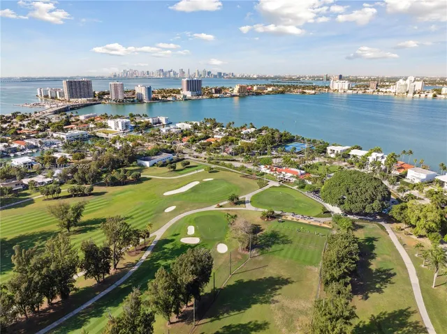 an aerial view of ocean and residential houses with outdoor space