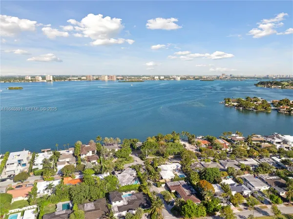 an aerial view of ocean and residential houses with outdoor space