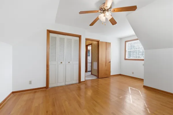 an empty room with chandelier fan and windows