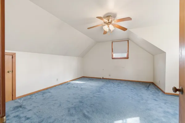 an empty room with a chandelier fan and windows