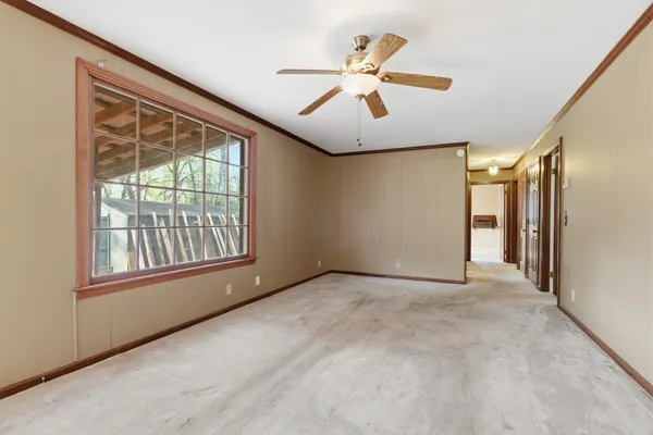 an empty room with chandelier fan and windows