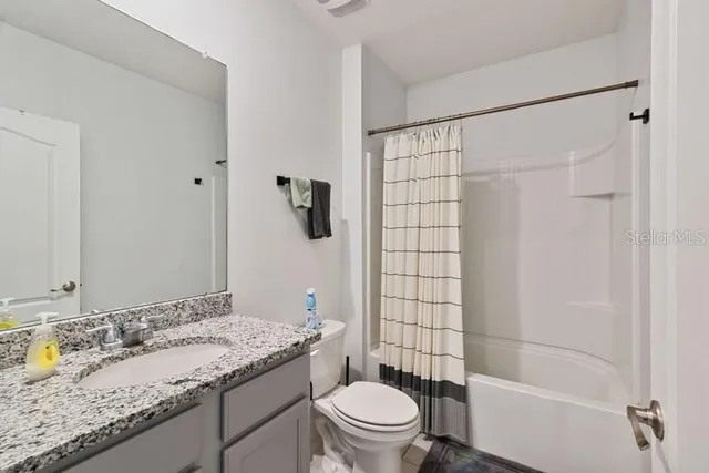a bathroom with a granite countertop sink a toilet and shower