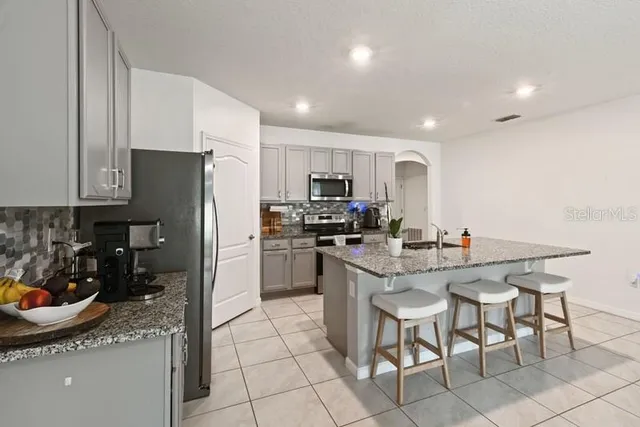a kitchen with a sink a refrigerator and chairs