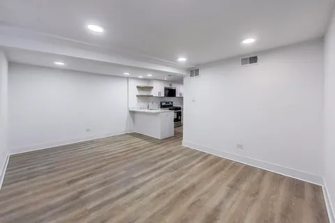 a view of kitchen and empty room with wooden floor