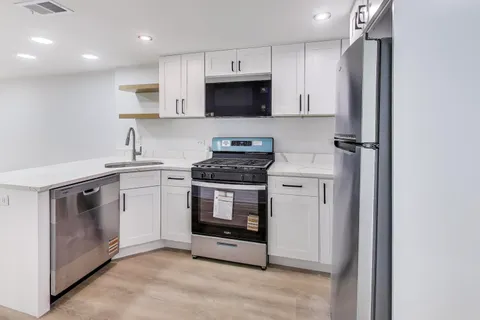 a kitchen with white cabinets and stainless steel appliances