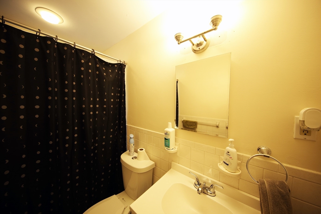23 Heath Street, Unit 1 Brookline, MA 02445 - Photo 15 of 16 a bathroom with a granite countertop sink a toilet and shower