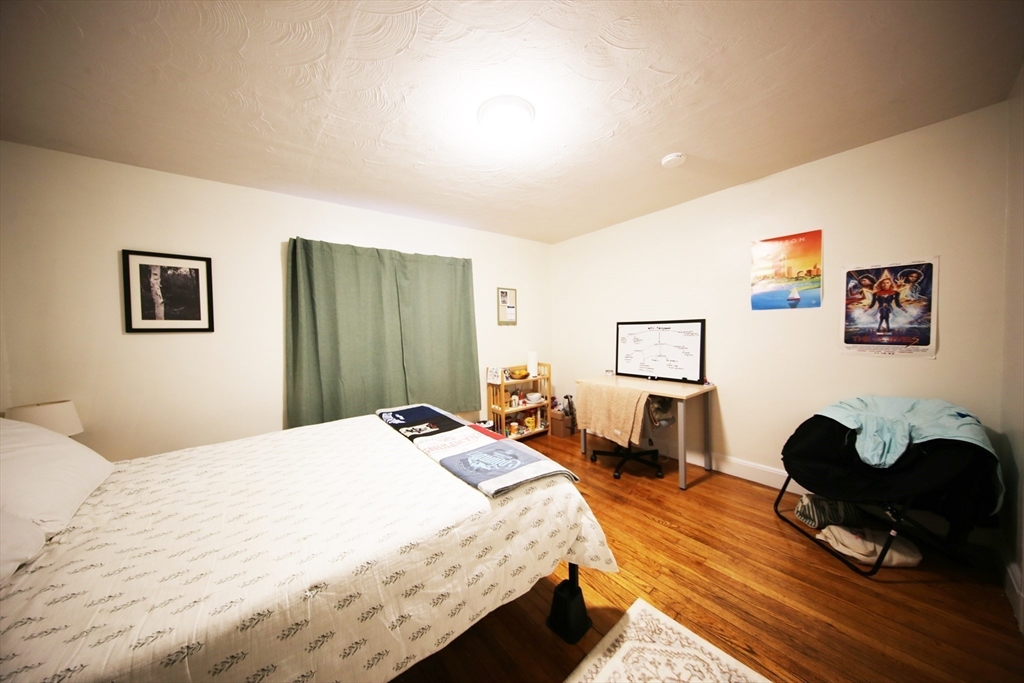 23 Heath Street, Unit 1 Brookline, MA 02445 - Photo 8 of 16 a bedroom with a bed a table and chair