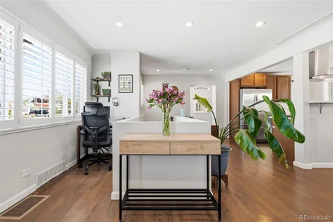 a living room with furniture a potted plant and open kitchen view