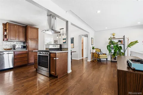 a kitchen with stainless steel appliances a stove a sink a refrigerator and wooden floor
