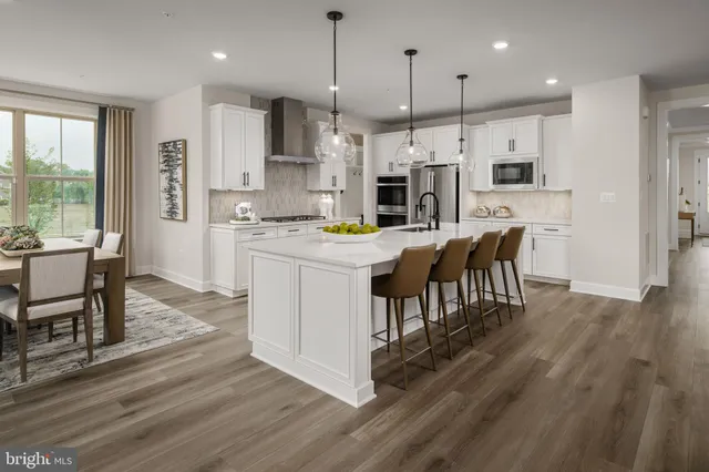 a kitchen with stainless steel appliances kitchen island granite countertop a table chairs and a refrigerator