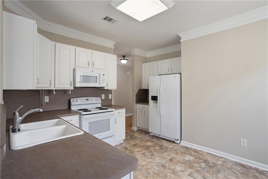 17 Williams Pride Way Newnan, GA 30265 - Photo 13 of 28 a kitchen with a refrigerator stove and white cabinets