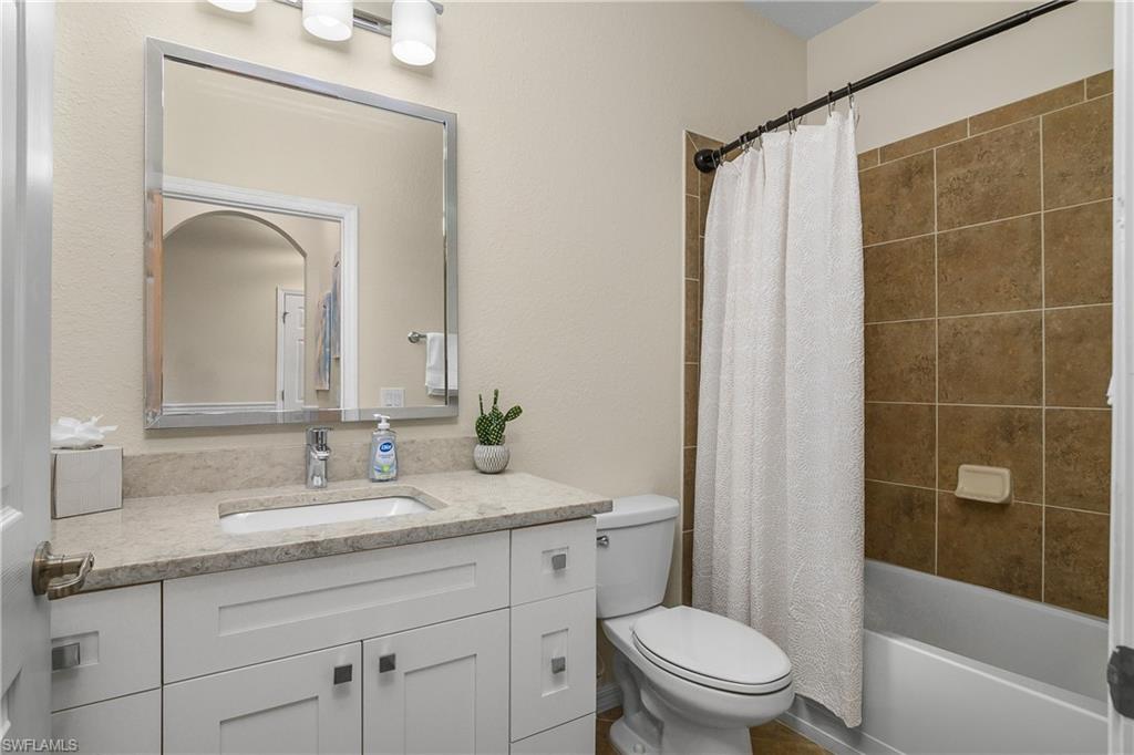 9834 Giaveno Circle, Unit 1746 Naples, FL 34113 - Photo 20 of 41 a bathroom with a granite countertop sink a toilet mirror and shower