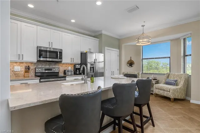 a kitchen with granite countertop a refrigerator a stove a sink a dining table and chairs with wooden floor