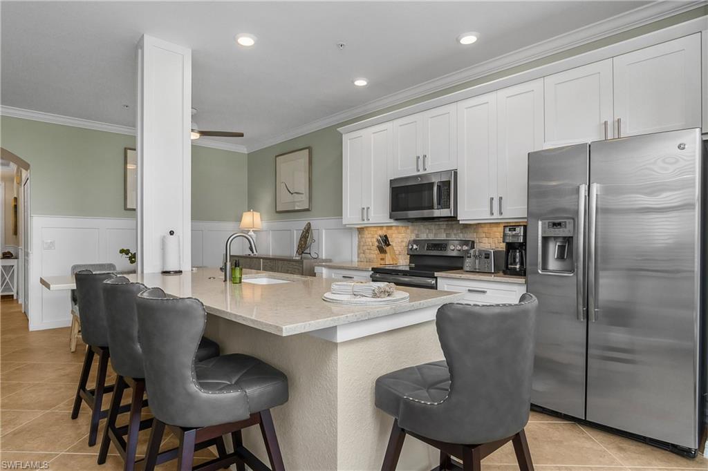 9834 Giaveno Circle, Unit 1746 Naples, FL 34113 - Photo 9 of 41 a kitchen with stainless steel appliances granite countertop a dining table chairs refrigerator and microwave