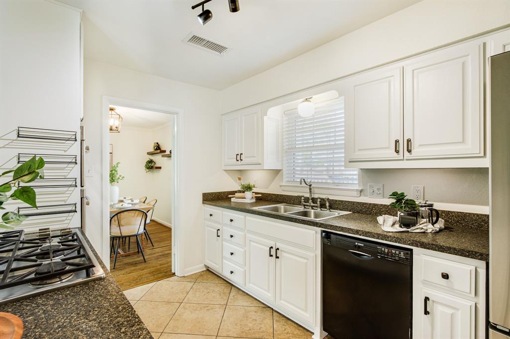 700 Ridgedale Drive Richardson, TX 75080 - Photo 15 of 32 This bright kitchen features crisp white cabinetry with black hardware, high-end stainless steel double ovens, and a built-in gas cooktop set against durable speckled countertops and neutral tile flooring.