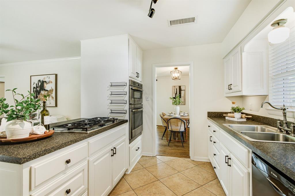 700 Ridgedale Drive Richardson, TX 75080 - Photo 16 of 32 This bright kitchen features crisp white cabinetry with black hardware, high-end stainless steel double ovens, and a built-in gas cooktop set against durable speckled countertops and neutral tile flooring.