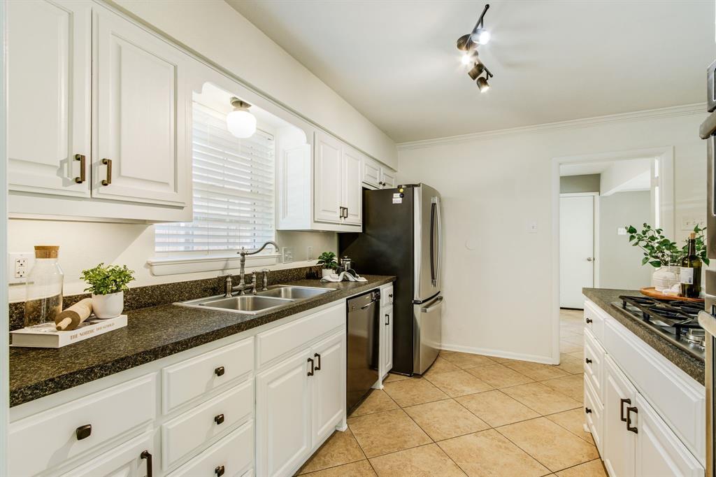 700 Ridgedale Drive Richardson, TX 75080 - Photo 17 of 32 This bright kitchen features crisp white cabinetry with black hardware, high-end stainless steel double ovens, and a built-in gas cooktop set against durable speckled countertops and neutral tile flooring.