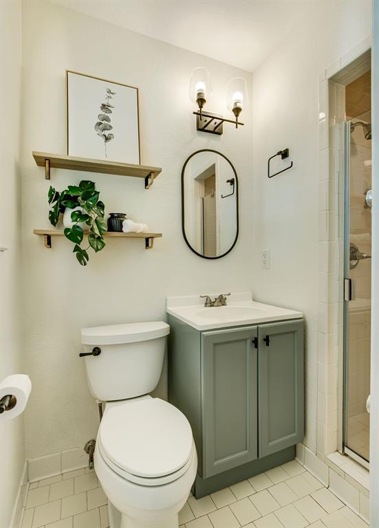 700 Ridgedale Drive Richardson, TX 75080 - Photo 21 of 32 A stylishly updated bathroom offers a sage green vanity with a clean white top, an oval matte black mirror, and a standing shower.