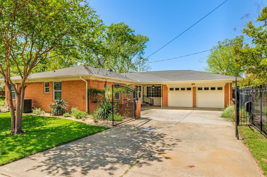 700 Ridgedale Drive Richardson, TX 75080 - Photo 28 of 32 A long concrete driveway leads to a rear-entry two-car garage, secured by a modern black wrought-iron power gate for added privacy and convenience.