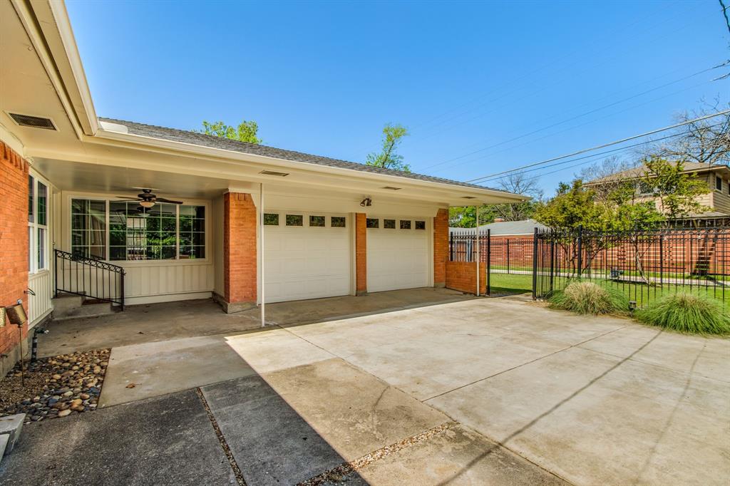 700 Ridgedale Drive Richardson, TX 75080 - Photo 30 of 32 A long concrete driveway leads to a rear-entry two-car garage, secured by a modern black wrought-iron power gate for added privacy and convenience.