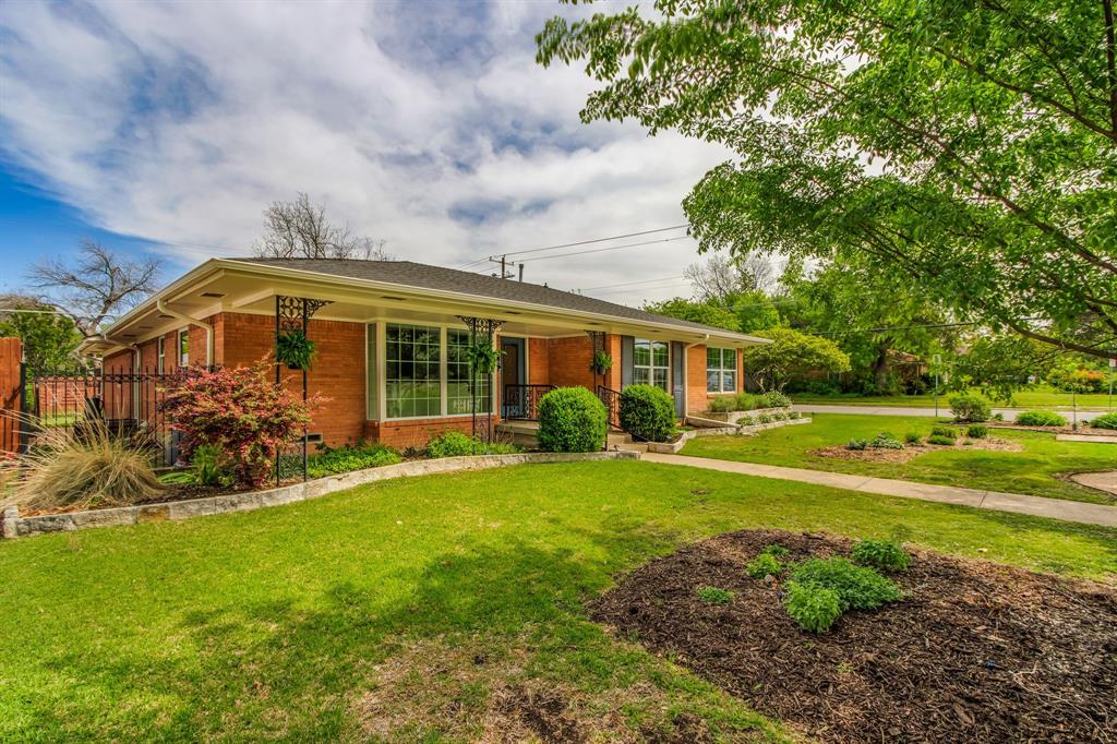 700 Ridgedale Drive Richardson, TX 75080 - Photo 4 of 32 A classic brick ranch-style home features large windows with decorative black iron security screens and shutters, framed by well-maintained landscaping with large front yard.