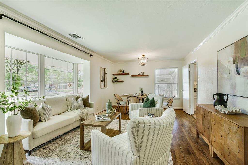 700 Ridgedale Drive Richardson, TX 75080 - Photo 8 of 32 Hardwood floors connect a light-filled family area featuring a large bay window with multi-paned glass, seamlessly transitioning into an open dining space.