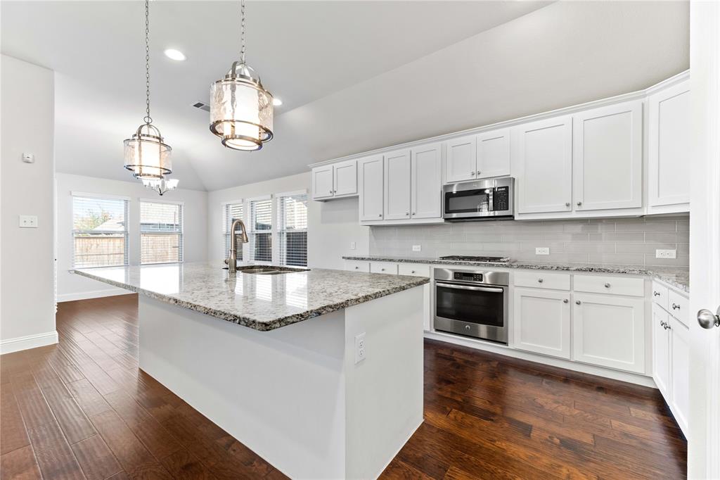 a kitchen with kitchen island granite countertop stainless steel appliances a stove center island a sink a stove and wooden floors