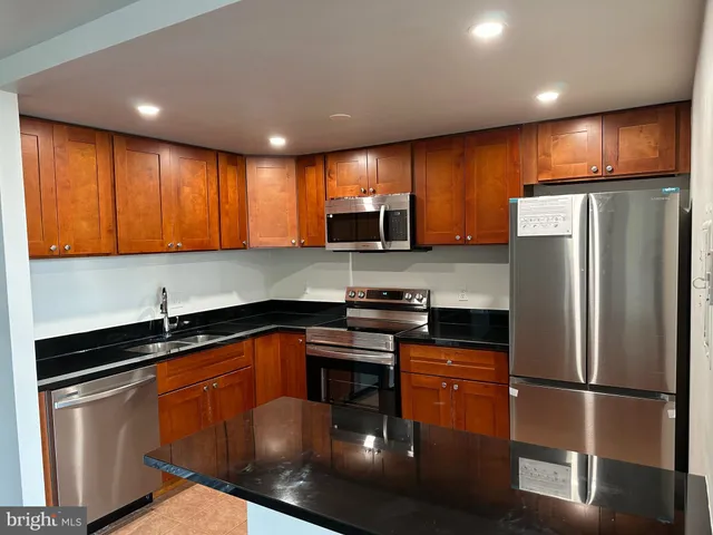 a kitchen with stainless steel appliances granite countertop a refrigerator a sink a stove a microwave and island