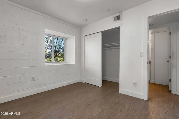 a view of an empty room with closet and wooden floor