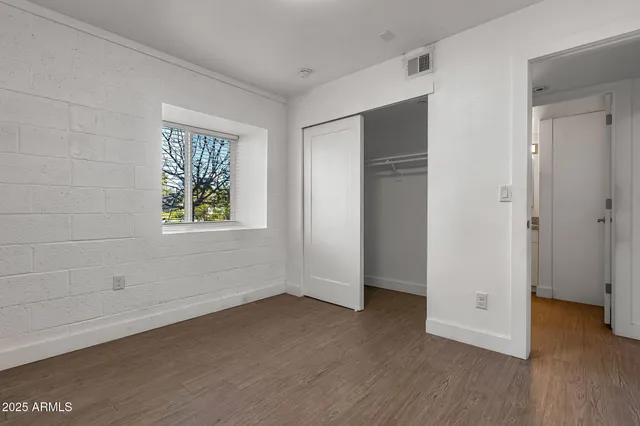 a view of an empty room with closet and wooden floor