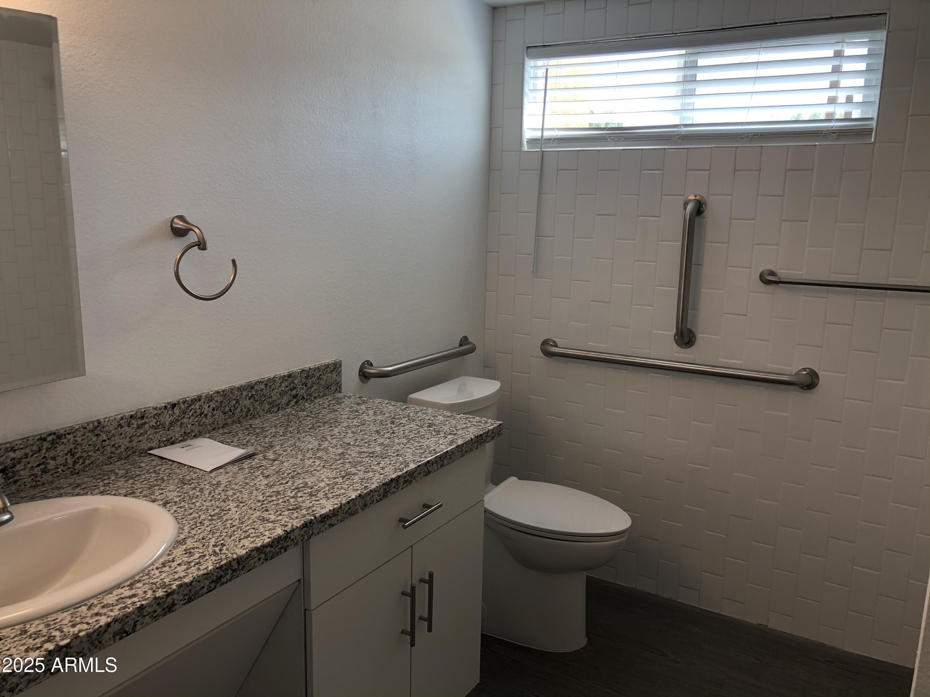 622 North 9th Avenue, Unit 101 Phoenix, AZ 85007 - Photo 16 of 18 a bathroom with a granite countertop sink a toilet and a mirror