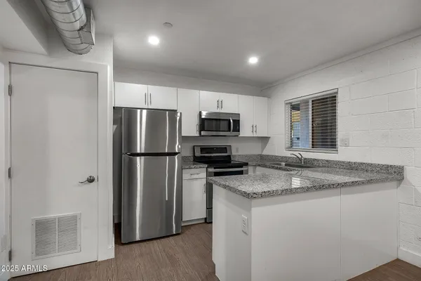 a kitchen with stainless steel appliances granite countertop a refrigerator a stove a sink and a microwave