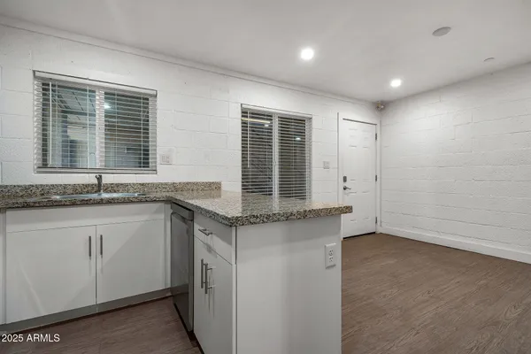 a kitchen with granite countertop a sink cabinets and stainless steel appliances