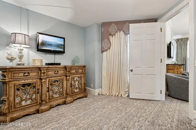 a living room with furniture a flat screen tv and a refrigerator