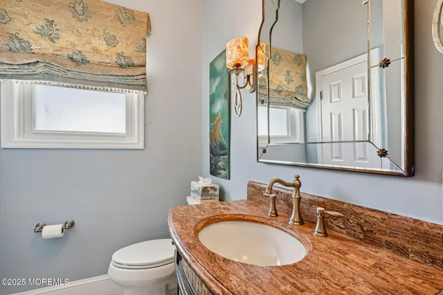 a bathroom with a granite countertop toilet a sink and a mirror