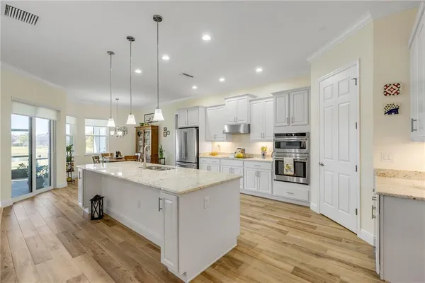 a large kitchen with kitchen island a stove a sink a refrigerator and cabinets