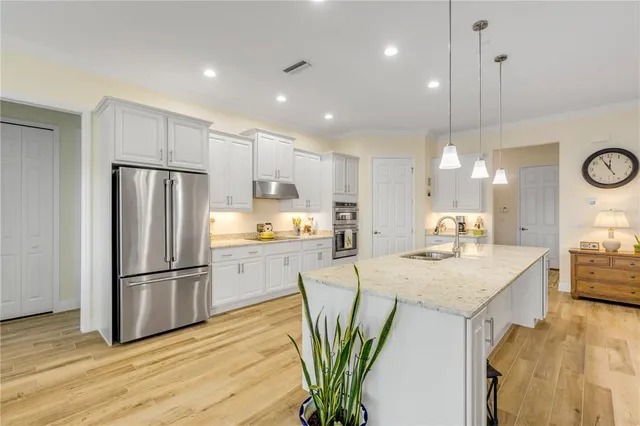 a kitchen with stainless steel appliances granite countertop a refrigerator a sink a stove and a wooden floors